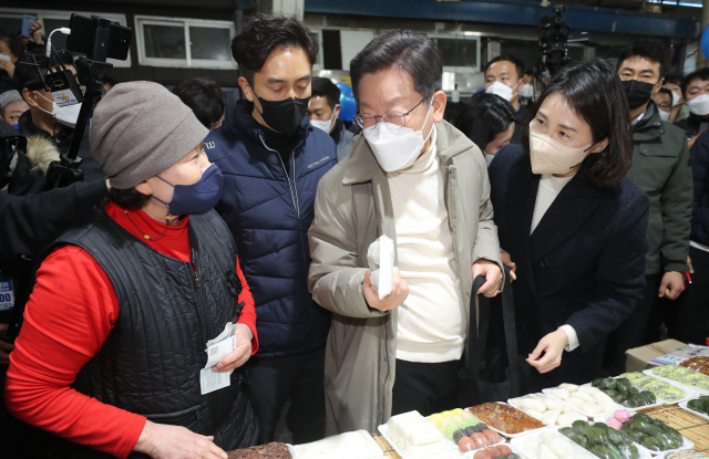 더불어민주당 이재명 대선 후보와 부인 김혜경 씨가 12일 조선시대 5대 시장으로 꼽히던 경북 김천시 김천 황금시장을 방문, 떡을 구입하고 있다. 연합뉴스