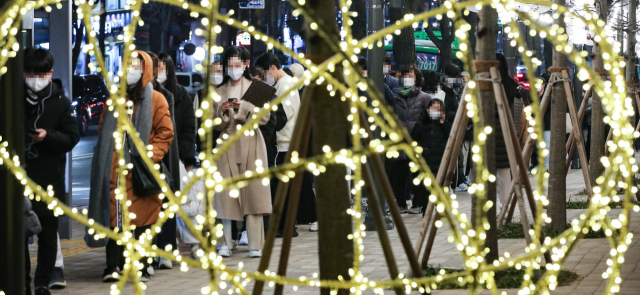 신종 코로나바이러스 감염증(코로나19) 신규 확진이 연일 7천 명대를 기록하는 등 방역 한계 상황에 다다르자 정부가 다시 사회적 거리두기 단계 강화를 발표한 16일 오후 서울 서대문구 신촌역 광장에 마련된 선별진료소를 찾은 시민들이 성탄과 연말을 상징하는 트리 조명 아래 코로나19 검사를 받기 위해 줄지어 서 있다. 연합뉴스