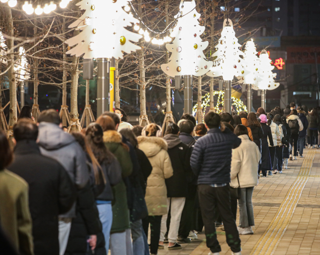 신종 코로나바이러스 감염증(코로나19) 신규 확진이 연일 7천 명대를 기록하는 등 방역 한계 상황에 다다르자 정부가 다시 사회적 거리두기 단계 강화를 발표한 16일 오후 서울 서대문구 신촌역 광장에 마련된 선별진료소를 찾은 시민들이 성탄과 연말을 상징하는 트리 조명 아래 코로나19 검사를 받기 위해 줄지어 서 있다. 연합뉴스