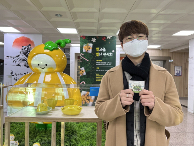 성주관광 UCC·굿즈 공모전 당선작 전시회장을 찾은 한 관람객이 성주관광 굿즈인 그립톡을 받고 기뻐하고 있다. 성주군 제공