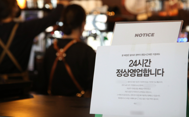 신종 코로나바이러스 감염증(코로나19) 확산으로 전국에 강화된 방역 조치가 시행 중인 21일 오후 경기도 용인의 한 카페에 정부의 영업시간 제한 조치에도 24시간 영업을 한다는 내용의 안내문이 부착돼 있다. 연합뉴스