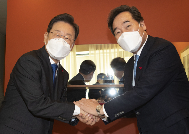 더불어민주당 이재명 대선 후보(왼쪽)와 이낙연 전 대표가 23일 서울 중구 달개비 식당에서 열린 오찬회동에서 손을 잡고 인사하고 있다. 국회사진기자단