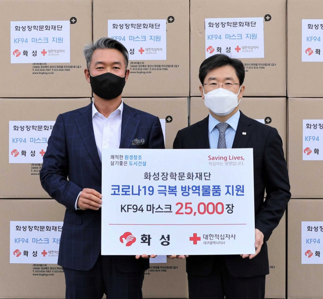 왼쪽부터 이종원 화성산업(주) 대표이사와 송준기 대구적십자사 회장이 2만 5천장 마스크 앞에서 전달식을 하고 있다.