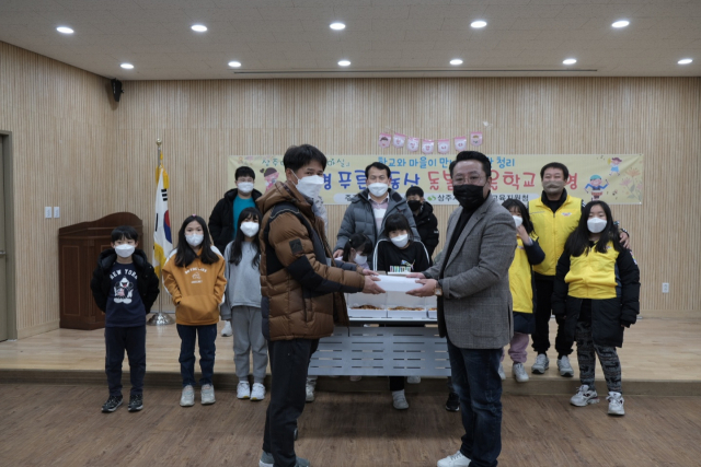 지난 30일 성민수(오른쪽) 희망상주재단 대표가 마을학교를 찾아 피자와 방역키트를 전달하고 있다. 희망상주재단 제공