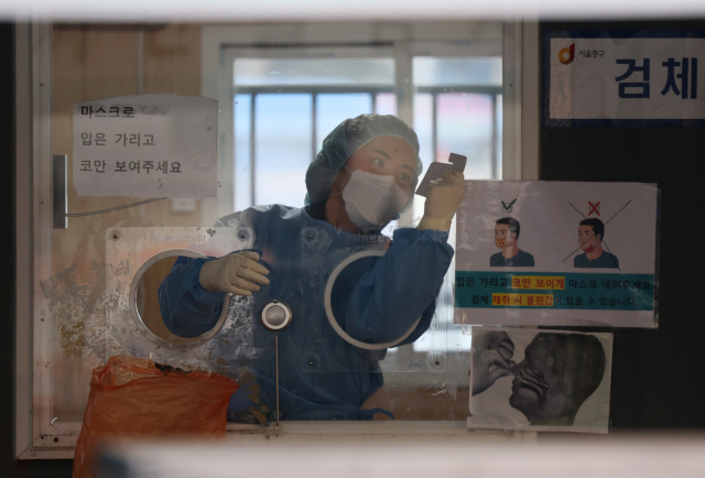 6일 오전 서울역 코로나19 임시 선별검사소에서 의료진이 유리벽에 붙은 얼음 조각을 긁어내고 있다. 연합뉴스