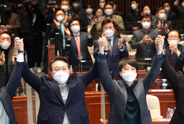 극한 대치 끝에 전격 화해한 국민의힘 윤석열 대선 후보와 이준석 대표가 6일 저녁 국회에서 열린 의원총회에서 손을 맞잡고 있다. 연합뉴스