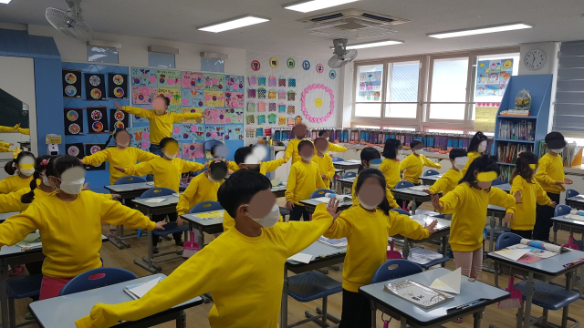 지난해 대구에 있는 한 초등학교 1학년 학급 모습. 학생 수 26명에 비해 교실이 비좁아 체조하는 것도 힘들다. 뒤에 있는 한 아이는 공간이 부족해서 단상 위에 올라가 체조를 하고 있다. 독자 제공