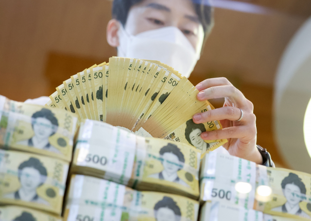 서울 중구 하나은행에서 직원이 5만원권을 펼쳐보이고 있다. 연합뉴스