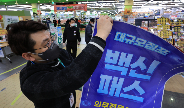 법원이 서울 마트·백화점에 대해 방역패스 효력 정지를 결정한 14일 오후 서울 서초구 양재동 농협하나로마트에서 관계자들이 방역패스 안내문을 치우고 있다. 연합뉴스