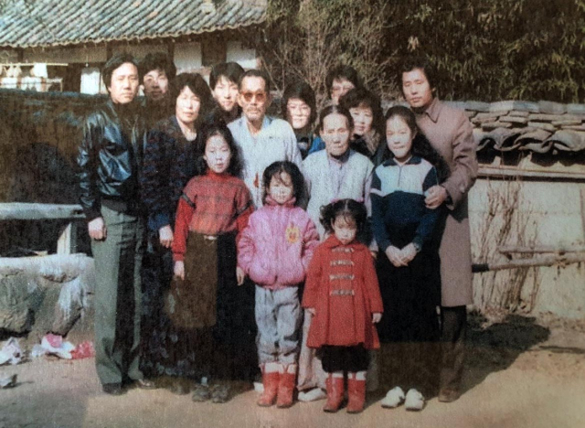 아버지○ 안용록 씨(사진 가운데 안경낀 사람)가 두 아들 내외의 가족과 시골 마당에서 함께 찍은 사진. 가족 제공.