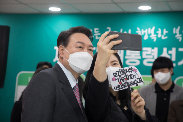 국민의힘 윤석열 대선 후보가 18일 서울 영등포구 사회복지사협회에서 간담회를 마치고 한 참석자의 셀카 촬영 요구에 응하고 있다. 연합뉴스