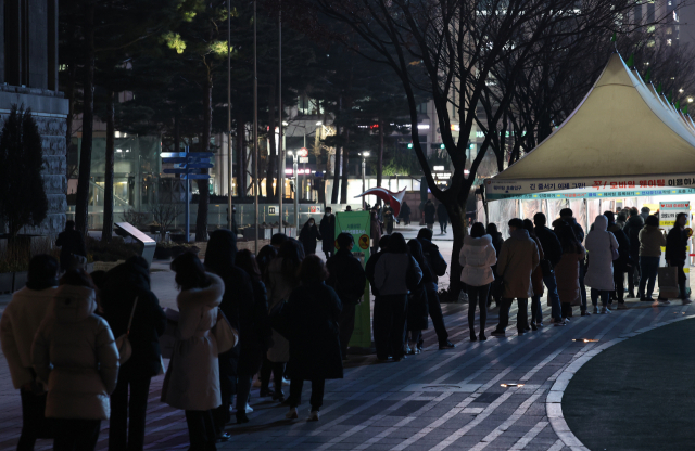 국내 오미크론 변이 확진자가 폭발적으로 증가하고 있는 27일 저녁 서울광장에 마련된 선별진료소를 찾은 시민들이 줄을 서서 검사를 기다리고 있다. 연합뉴스