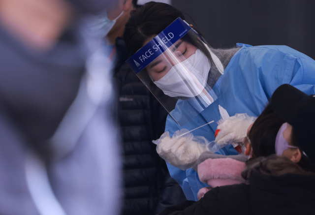 27일 서울 중구 서울역 광장 코로나19 임시 선별검사소에서 의료진이 어린이 검사를 위해 부스에서 나와 검체를 채취하고 있다. 중앙방역대책본부는 이날 0시 기준으로 신규 확진자가 1만4천518명 늘어 누적 77만7천497명이라고 밝혔다. 전날 1만3천10명에서 하루 사이에 1천508명이 늘었다. 연합뉴스
