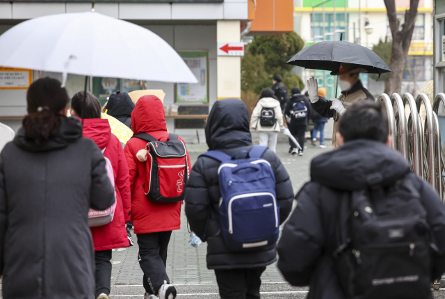 25일 오전 개학을 맞은 서울의 한 초등학교에서 학생들이 학교보안관과 인사를 나누며 등교하고 있다. 연합뉴스