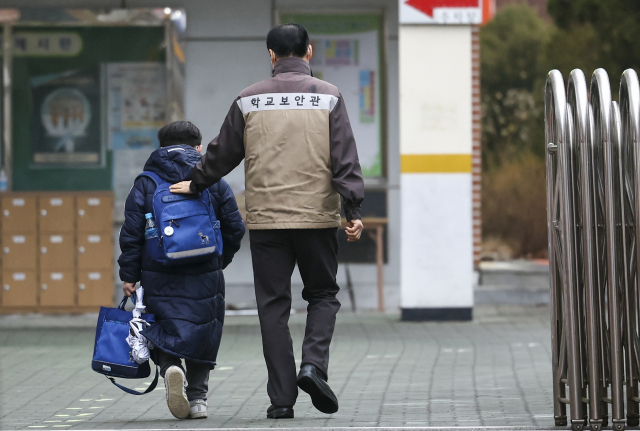 25일 오전 개학을 맞은 서울의 한 초등학교에서 한 학생이 보안관과 대화하며 등교하고 있다. 연합뉴스