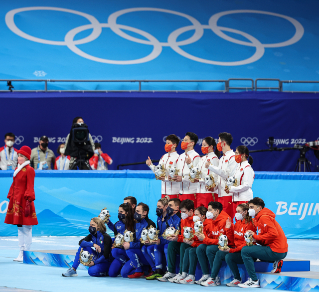 5일 베이징 캐피털 실내 경기장에서 열린 2022 베이징 동계올림픽 쇼트트랙 남녀 혼성계주 결승 뒤 열린 플라워 세리머니에서 1위를 차지한 중국(가운데), 2위 이탈리아(왼쪽), 3위 헝가리 선수들이 축하꽃을 들고 기념촬영을 하고 있다. 연합뉴스