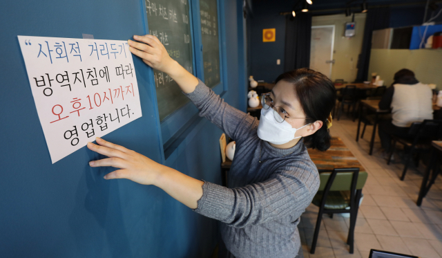 정부가 식당·카페 등 영업시간 제한을 밤 10시로 1시간 연장하기로 발표한 18일 오후 대구 중구의 한 식당에서 관계자가 영업제한 시간 변경 안내문을 붙이고 있다. 이번 거리두기 조정안은 19일부터 다음달 13일까지 약 3주간 시행된다. 김영진 기자 kyjmaeil@imaeil.com