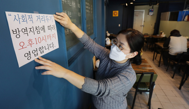 정부가 식당·카페 등 영업시간 제한을 밤 10시로 1시간 연장하기로 발표한 18일 대구 중구의 한 식당에서 관계자가 영업제한 시간 변경 안내문을 붙이고 있다. 이번 거리두기 조정안은 19일부터 다음달 13일까지 약 3주간 시행된다. 김영진 기자 kyjmaeil@imaeil.com