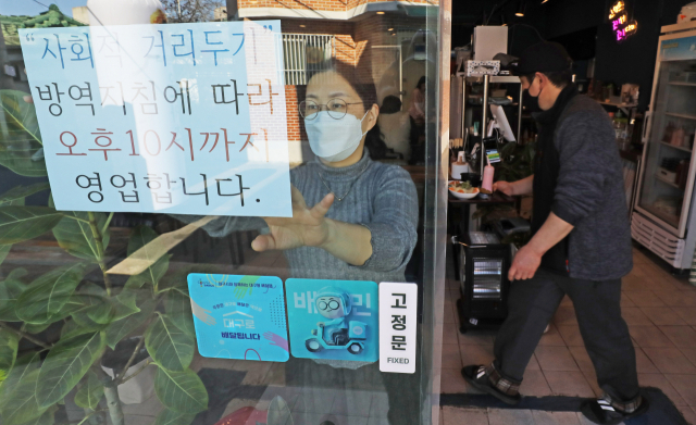 정부가 식당·카페 등 영업시간 제한을 오후 10시로 한 시간 연장하기로 발표한 18일 오후 대구 중구의 한 식당에서 관계자가 영업제한 시간 변경 안내문을 붙이고 있다. 이번 거리두기 조정안은 19일부터 다음달 13일까지 약 3주간 시행된다. 김영진 기자 kyjmaeil@imaeil.com