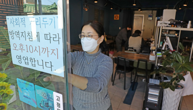 정부가 식당·카페 등 영업시간 제한을 밤 10시로 1시간 연장하기로 발표한 18일 오후 대구 중구의 한 식당에서 관계자가 영업제한 시간 변경 안내문을 붙이고 있다. 이번 거리두기 조정안은 19일부터 다음달 13일까지 약 3주간 시행된다. 김영진 기자 kyjmaeil@imaeil.com