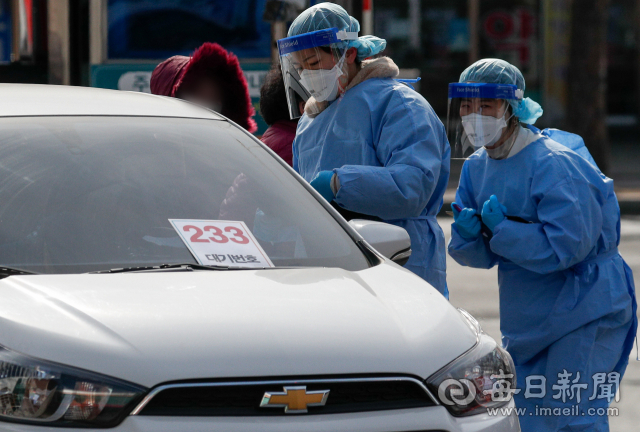 지난 23일 대구의료원 선별진료소에서 의료진이 차량에 대기번호를 붙인 채 코로나19 진단 검사를 기다리는 시민을 안내하고 있다. 매일신문 DB