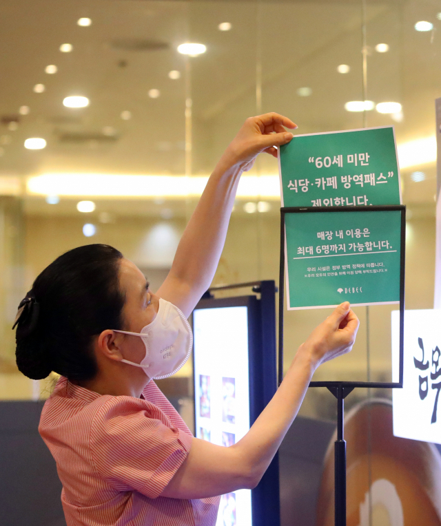 24일 오전 대구 중구 대구백화점 프라자점 내 식당 직원이 방역패스 안내문을 교체하고 있다. 전날 대구지법은 청소년 방역패스에 이어 60세 미만에 대한 식당·카페 방역패스 효력정지 결정을 내렸다. 연합뉴스