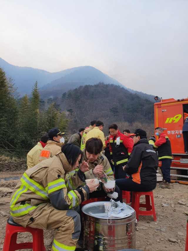 밤새 산불을 진압에 나선 소방서 직원들이 산불이 소강상태를 보이자 컵라면과 김밥으로 아침을 먹고 있다. 뒷쪽으로 이철우 경북도지사와 곽용환 고령군수가 보인다. 이채수 기자