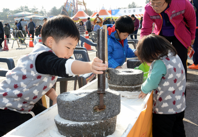 코로나 팬데믹 이전에 열린 파주장단콩축제장에서 어린이들이 멧돌로 콩갈기 체험을 하고 있다.