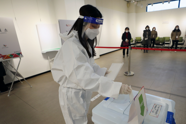 제20대 대통령선거 사전 투표 이틀째인 5일 오후 광주 서구 학생교육문화회관에 마련된 상무1동 사전투표소에서 확진·격리자들이 투표한 투표용지를 방역복을 입은 관계자가 전달받아 투표함에 넣고 있다. 연합뉴스