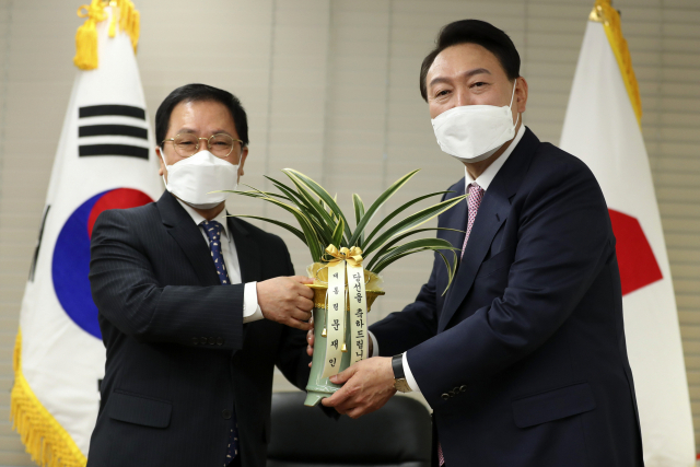 윤석열 대통령 당선인이 10일 오후 서울 여의도 국민의힘 당사에서 유영민 대통령 비서실장으로부터 문재인 대통령의 축하난을 받고 있다. 연합뉴스