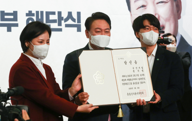 윤석열 대통령 당선인이 10일 오후 서울 여의도 국회도서관에서 열린 국민의힘 대선 선거대책본부 해단식에서 중앙선거관리위원회로부터 받은 당선증을 청년보좌역에게 전달받고 있다. 연합뉴스