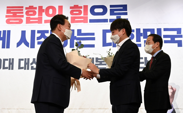 윤석열 대통령 당선인이 10일 오후 국회 도서관에서 열린 국민의힘 선대본부 해단식에서 이준석 대표와 권영세 선대본부장으로부터 꽃다발을 받고 있다. 연합뉴스
