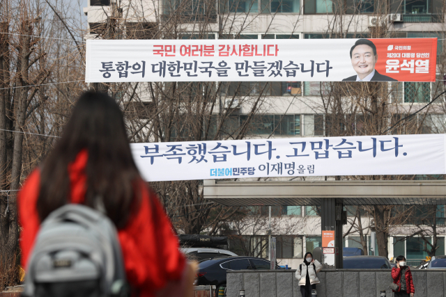 윤석열 제20대 대통령 당선인의 재건축 규제 완화 공약에 서울을 중심으로 한 주요 재건축 추진 단지들의 기대감이 커지고 있다. 업계에 따르면 대선 결과 발표 직후 당장 실거래가 성사되거나 문의가 폭주하는 것은 아니지만, 서울 주요 재건축 추진 단지 아파트의 호가가 이전보다 높게 형성되거나 시중에 나왔던 매물이 회수되는 분위기다. 사진은 11일 서울 한 아파트 단지 앞에 내걸린 윤석열 대통령 당선인과 더불어민주당 이재명 대선 후보 메시지. 연합뉴스