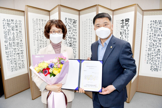 박춘남 문경시의원(왼쪽)이 전국여성지방의원 우수사례공모에서 우수의정 대상 수상자로 결정된 후 김창기 문경시의회 의장으로부터 축하 꽃다발을 전달받았다. 문경시의회 제공.