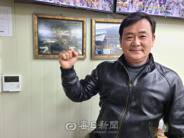 안동신시장마트 정성재 대표가 마트에 화재로 피해를 입었던 당시 사진 앞에서 화이팅 포즈를 취하고 있다. 정 대표는