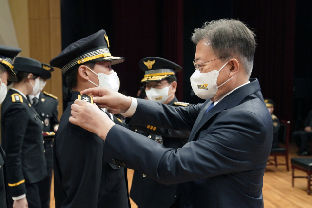 문재인 대통령이 17일 오후 충남 아산 경찰대학에서 열린 2022년 신임경찰 경위·경감 임용식에서 임용자 대표 어깨에 계급장을 부착하고 있다. 연합뉴스