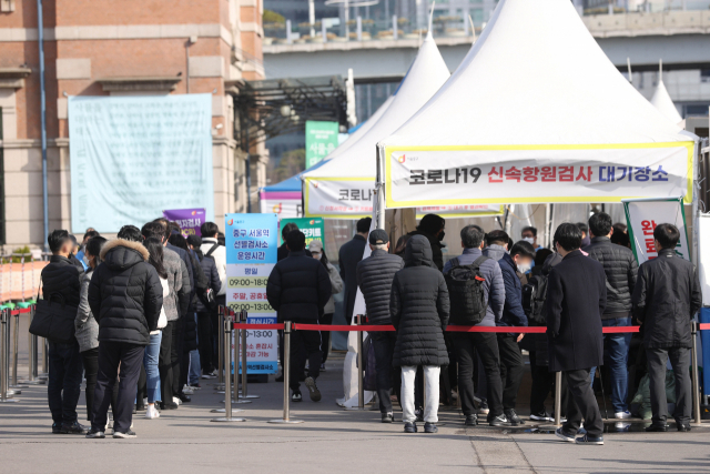 21일 오전 서울역 선별진료소에서 시민들이 신속항원검사 결과를 기다리고 있다. 중앙방역대책본부는 21일 0시 기준 코로나19 신규 확진자가 20만9,169명 집계됐다고 밝혔다. 연합뉴스