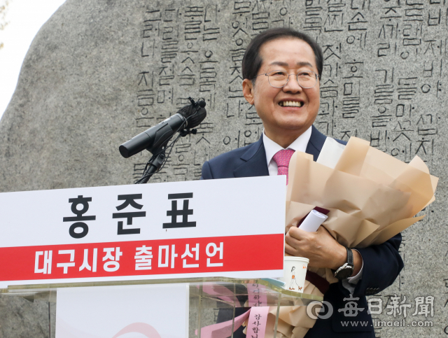 홍준표 국민의힘 의원이 31일 대구 수성못 상화동산에서 대구시장 출마선언을 한 뒤 지지자로부터 받은 꽃다발을 들고 웃고 있다. 그는