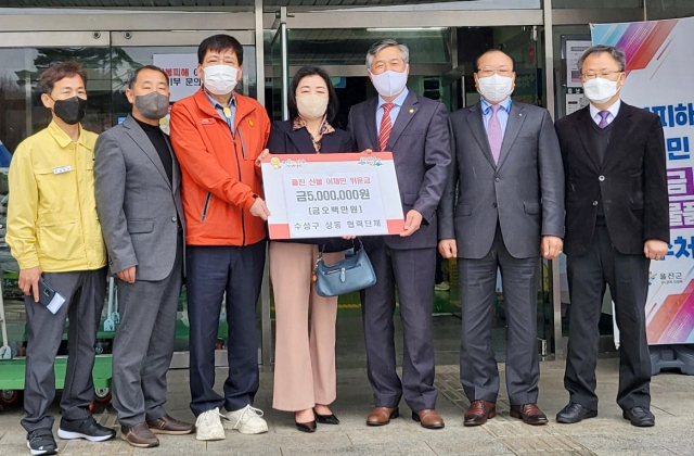 박은용(왼쪽에서 5번째) 수성구 상동 주민자치위원장이 지난달 31일 산불 피해를 입은 울진읍 울진국민체육관을 찾아 상동 협력단체에서 모금한 성금을 최선광(왼쪽에서 3번째) 울진읍장에게 전달하고 있다.