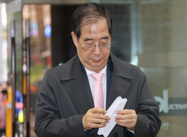 한덕수 국무총리 후보자가 14일 오전 서울 종로구 한국생산성본부 건물에 마련된 국회 인사청문회 준비단 사무실에 출근하며 마스크를 쓰지 않은 것을 뒤늦게 알고 꺼내고 있다. 연합뉴스