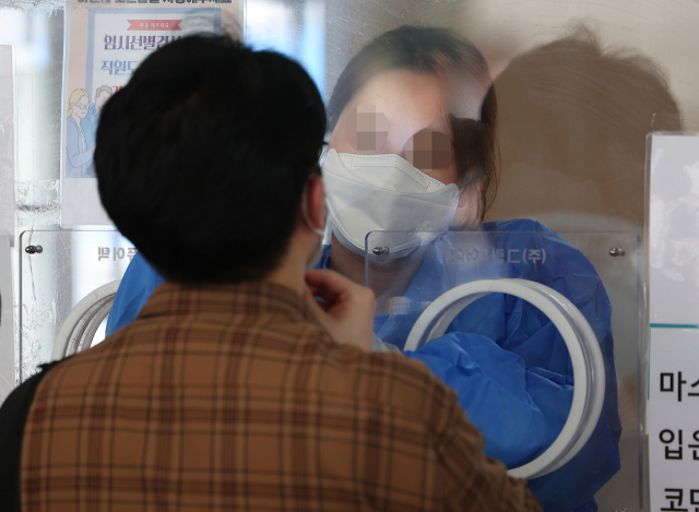 코로나19 선별진료소와 임시선별검사소 신속항원검사 중단 이틀째인 12일 오전 서울역광장에 마련된 임시선별검사소에서 의료진이 검체 채취를 하고 있다. 한편 중앙방역대책본부에 따르면 이날 신규확진자 수는 21만755명으로 집계됐다. 연합뉴스