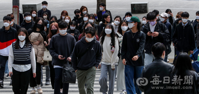 정부가 2020년 3월부터 2년 1개월간 이어온 사회적 거리두기를 전면 해제한다고 밝힌 15일 오전 대구 북구 경북대학교 북문 앞에서 마스크를 쓴 학생들이 길을 건너고 있다. 이날 김부겸 총리는 실외마스크 착용에 대해서 
