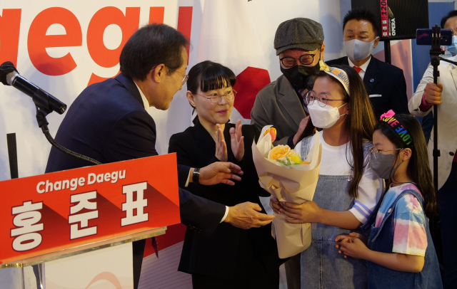 홍준표 국민의힘 대구시장 예비후보가 지난 16일 대구 중구 선거사무소 개소식에서 어린이들에게 꽃다발을 받고 있다.