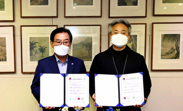 백선기(왼쪽) 칠곡군수와 박현동 왜관수도원장이 양봉요지 반환 협약서를 들어보이고 있다. 칠곡군 제공