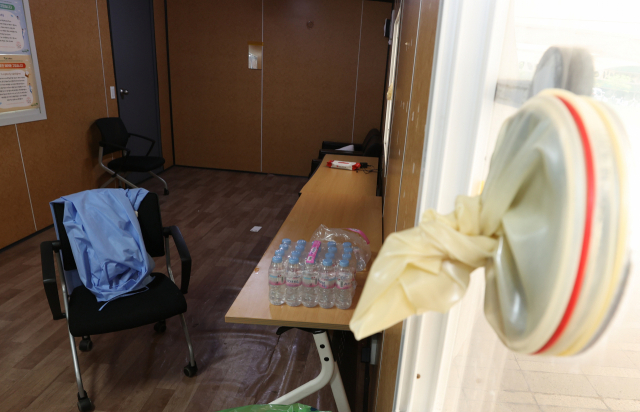 22일 오후 철거 중인 서울광장 코로나19 임시선별검사소 내부에 의료진이 사용하던 방역복이 놓여 있고 오른쪽 창문엔 검체채취용 장갑이 묶여 있다. 지난 15일 서울시는 거리두기 전면 해제에 따라 