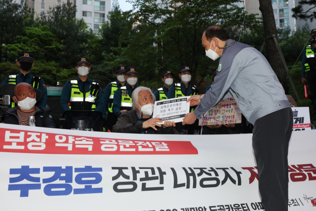 박경석 전국장애인차별철폐연대(전장연) 공동대표가 23일 오후 서울 강남구 레미안도곡카운티 아파트 단지 입구에서 기자회견을 열어 추경호 경제부총리 겸 기획재정부 장관후보자에게 요구하는 장애인 권리예산 보장 약속 공문을 해당 아파트 관리과장에게 전달하고 있다. 연합뉴스