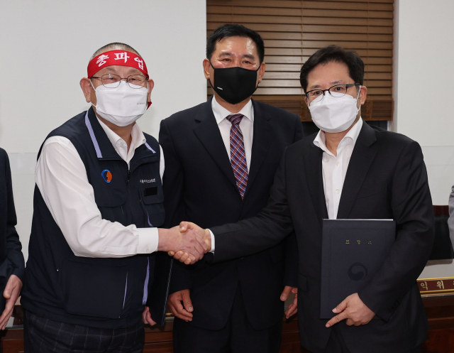 서울 시내버스 노사가 임금협상 1차 사후조정에서 협상을 타결한 26일 새벽 서울 영등포구 서울지방노동위원회에서 박점곤 서울시버스노동조합 위원장(왼쪽)과 조장우 서울시버스운송사업조합 이사장이 악수를 하고 있다. 연합뉴스