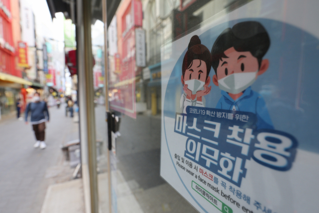 27일 오후 서울 중구 명동거리의 한 매장에 붙은 마스크 착용 의무화 안내문.