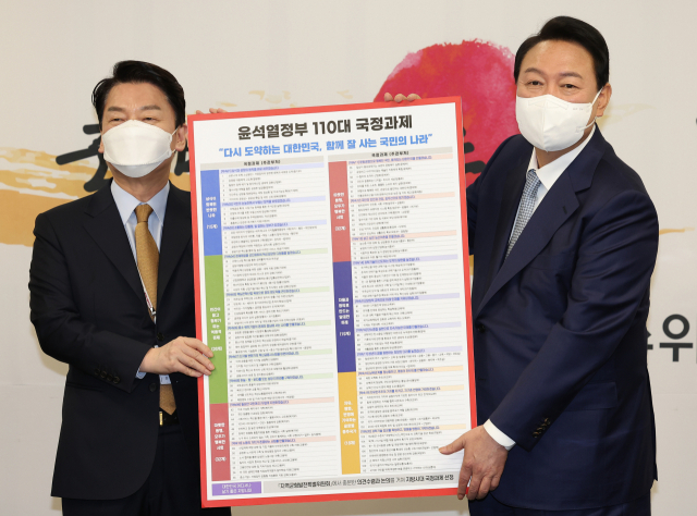 윤석열 20대 대통령 당선인이 3일 오전 서울 종로구 삼청동 대통령직인수위원회에서 열린 전체 회의에서 안철수 인수위원장으로부터 인수위가 준비한 110대 국정과제를 전달받고 있다. 연합뉴스