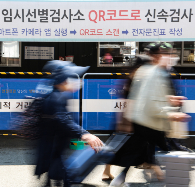 16일 코로나19 신규 확진이 104일 만에 1만 명대를 기록해 한산해진 서울 중구 서울역 코로나19 선별검사소 앞을 시민들이 지나치고 있다. 연합뉴스